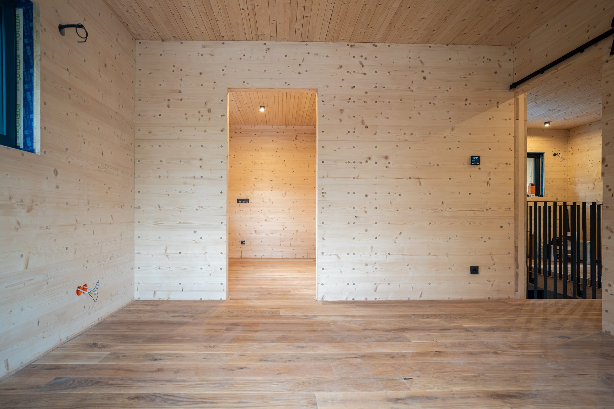 Innenraum eines Holz100-Hauses: sichtbare Massivholzwände mit Holzdübeln, Holzdecke und Eichendielen