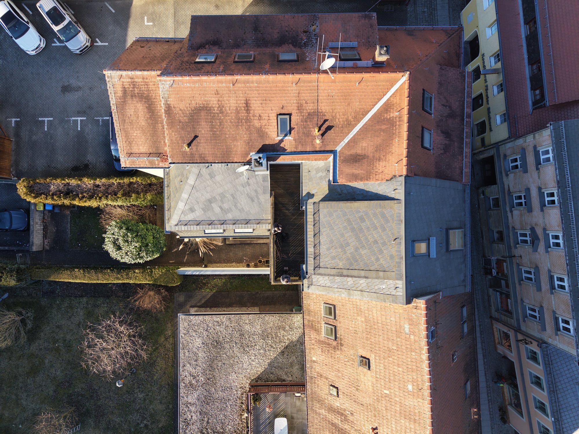 Luftbild eines Bestandsgebäudes mit Ziegel- und Schieferdächern und Dachterrasse