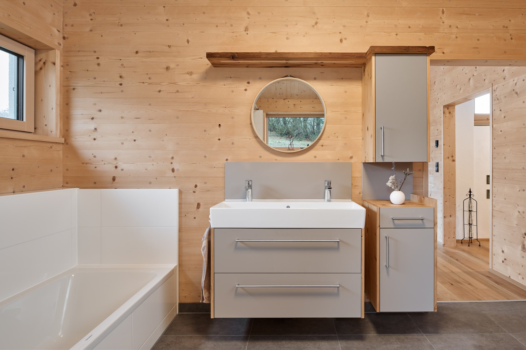 Bad mit Doppelwaschtisch und Badewanne vor sichtbarer Massivholzwand